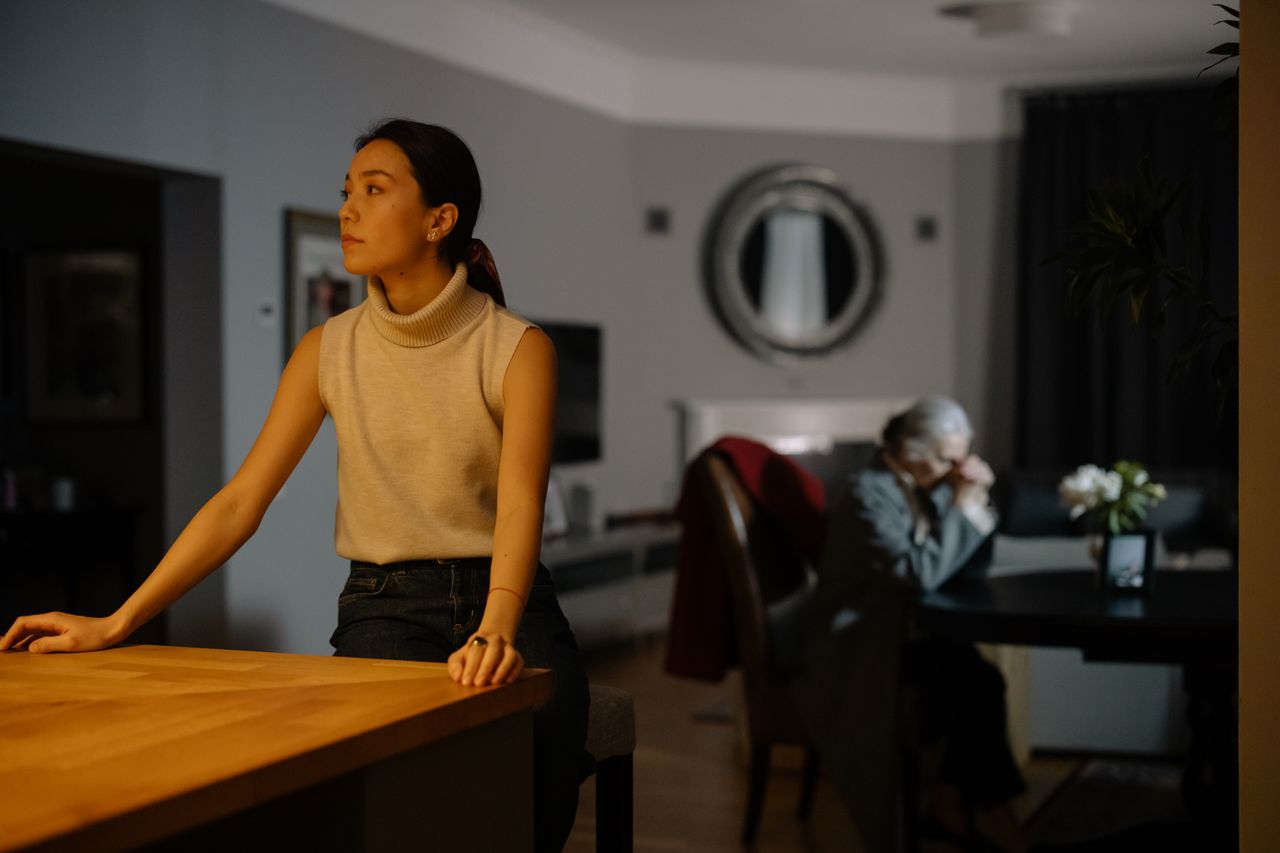 Older parent reflecting near a window, representing family distance, dignity, and stepping back from a difficult family relationship
